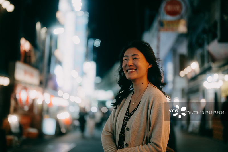 快乐的女人在夜晚的城市，东京图片素材
