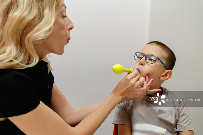 在职业治疗中吹气球的小学年龄男孩，由女专家辅助图片素材