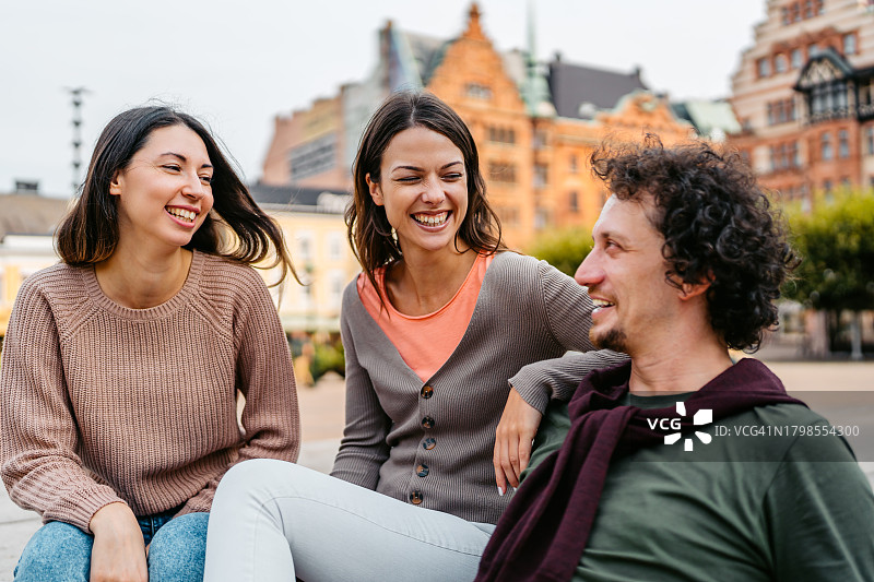 三个年轻的朋友坐在瑞典马尔默的Stortorget广场的台阶上图片素材