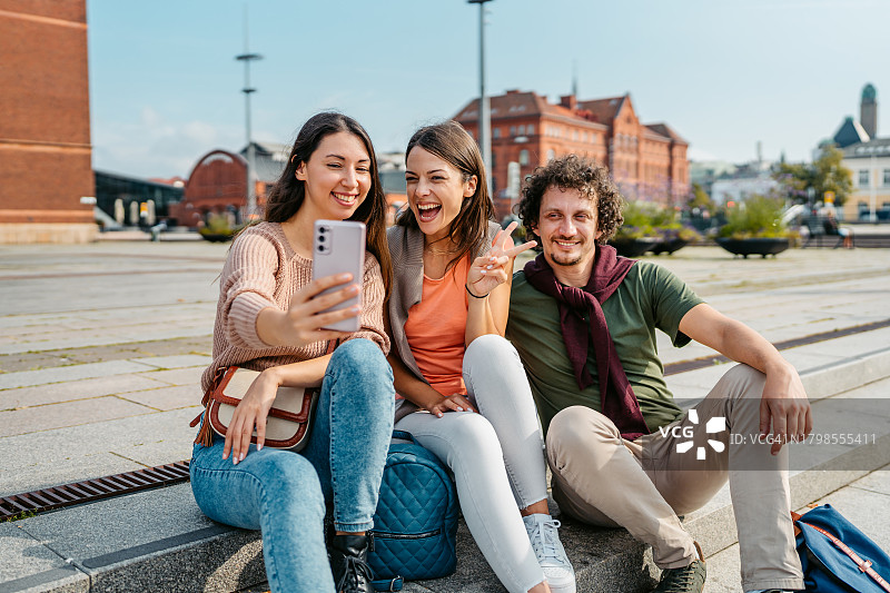 瑞典马尔默邮局前三个年轻朋友在台阶上自拍图片素材