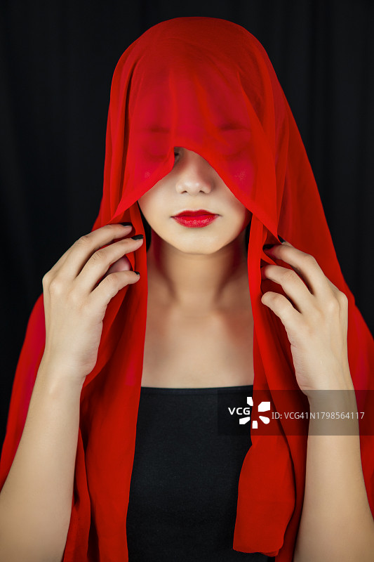 用红色围巾遮住头并向下看的女子肖像图片素材