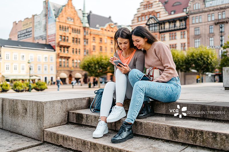 两位女性朋友瑞典马尔默大广场台阶上使用手机图片素材