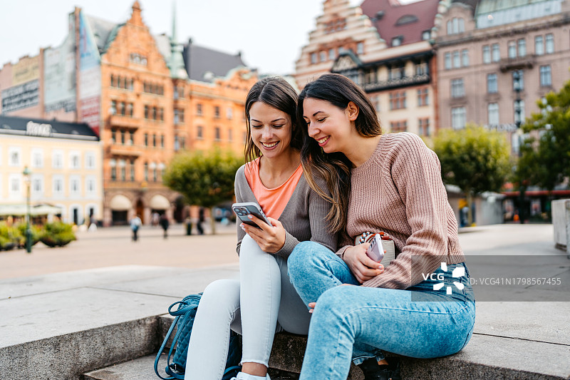 两位女性朋友瑞典马尔默大广场台阶上使用手机图片素材