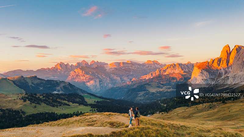 情侣带狗在多洛米蒂山脉欣赏日落美景航拍图片素材