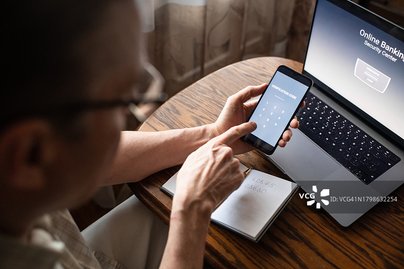 严重的老年男子在家输入智能手机的验证码，防止欺诈的概念。图片素材