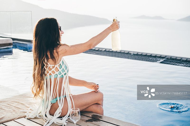 女人在游泳池边倒白葡萄酒图片素材
