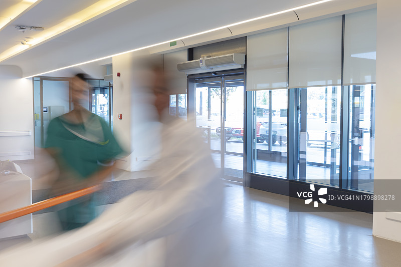 医护人员用担架将病人从救护车送到医院。两名医护人员和一名病人。现代救护车。大型医院急诊室入口图片素材