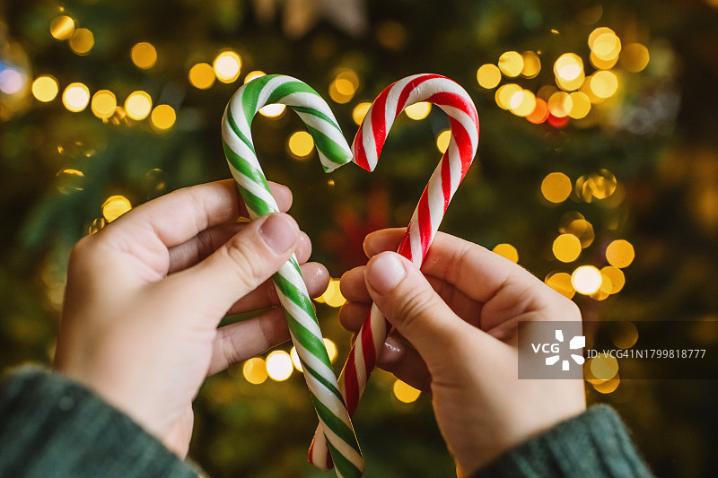 圣诞树背景上手持心形拐杖糖的儿童图片素材