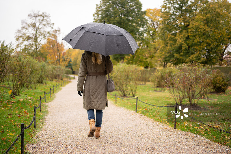 在雨中穿过公园的女人图片素材