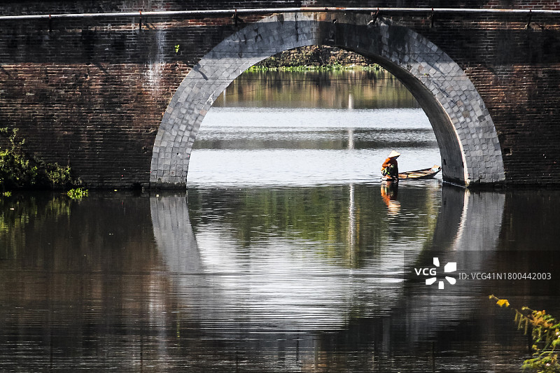 女人在护城河的舢板船上捕捞蜗牛和鱼图片素材
