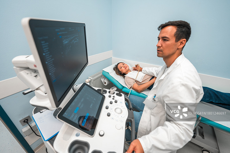 亚洲男性超声医师进行甲状腺超声检查图片素材