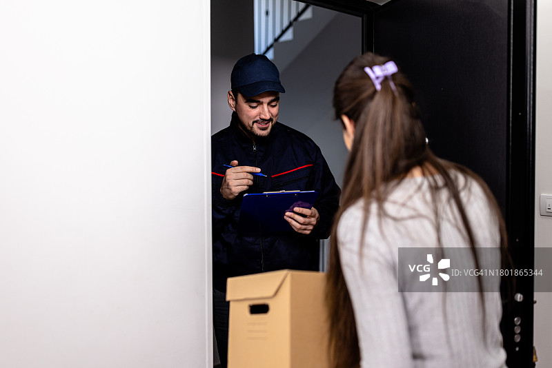 年轻快递员为年轻女子送纸箱上门图片素材