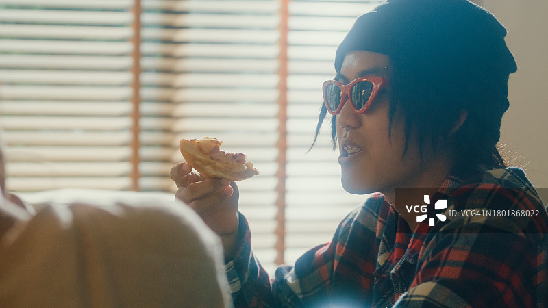 亚洲年轻人在家吃披萨的特写图片素材