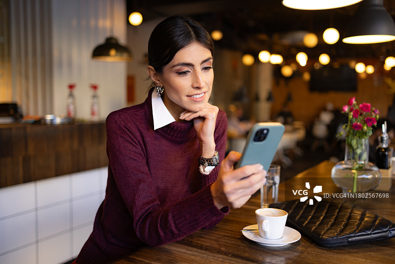在咖啡馆等待时使用手机的女商人图片素材