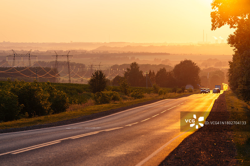 夕阳下，沿着电力线延伸的公路图片素材