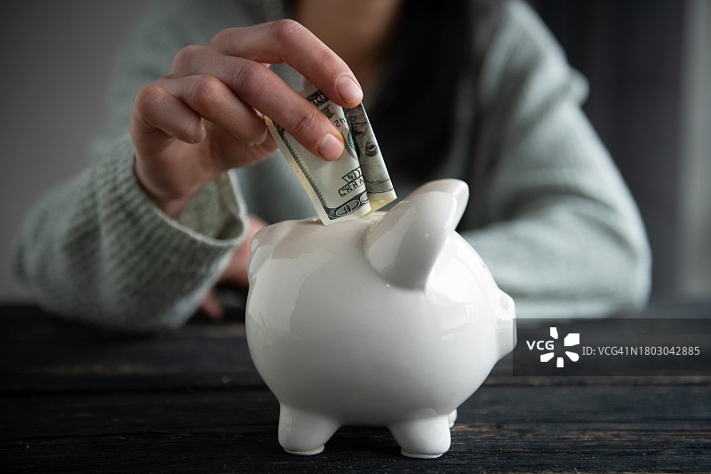 手持金钱与小猪储蓄罐图片素材