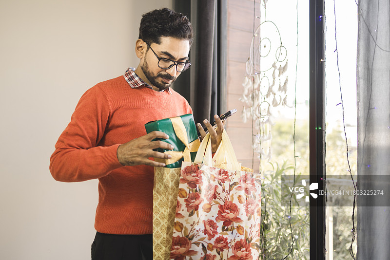 身穿休闲商务装，手提圣诞购物袋的年轻人图片素材