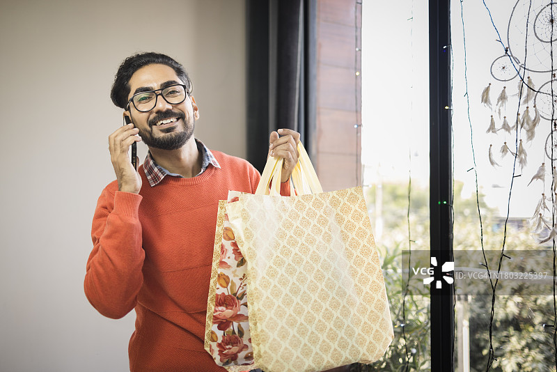 身穿休闲商务装，手提圣诞购物袋的年轻人图片素材