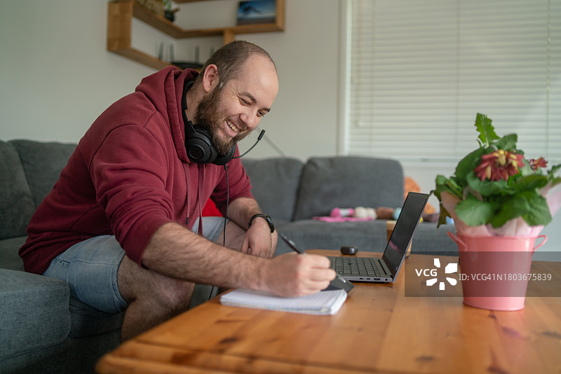 年轻男子在家办公时做笔记图片素材