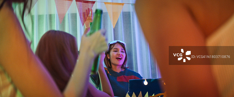 年轻亚洲女人在夜晚家庭派对上打碟图片素材