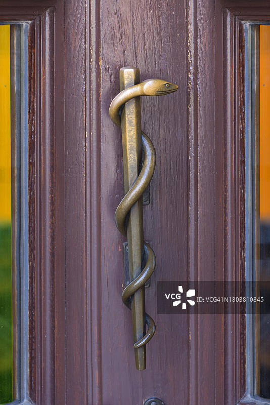 埃尔兰根药房上的黄铜阿斯克勒庇俄斯之杖门把手,德国巴伐利亚州中弗兰肯图片素材