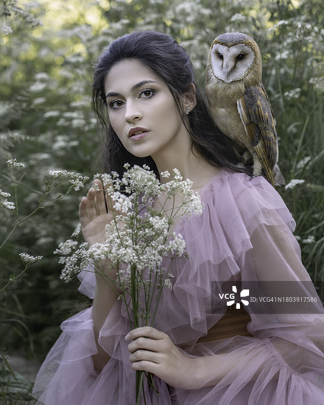 身穿粉色晨衣，与猫头鹰和鲜花的女孩特写图片素材