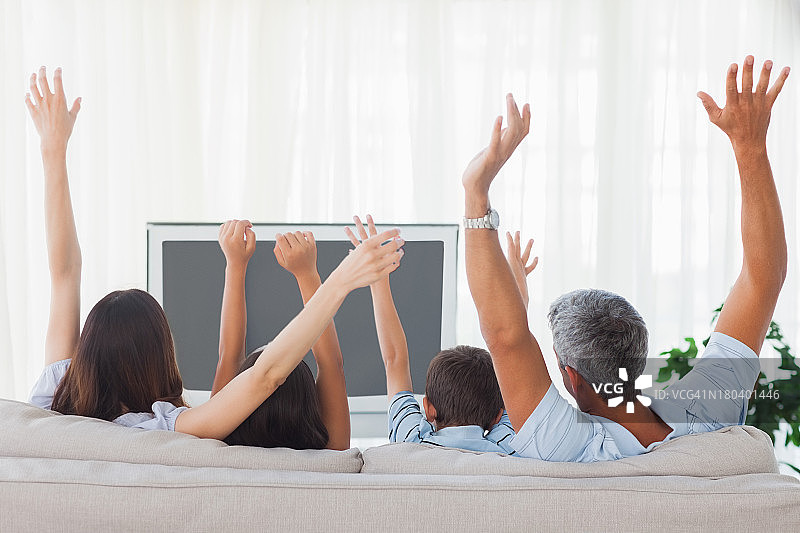 一家人看电视并举起手臂图片素材