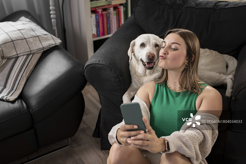年轻女人在家嘟嘴和狗狗自拍图片素材