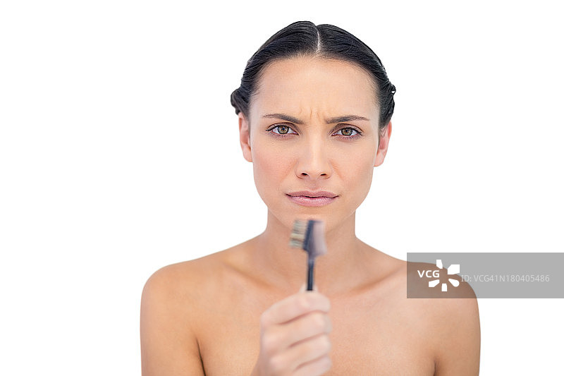 拿着眉刷的严肃美丽年轻模特图片素材