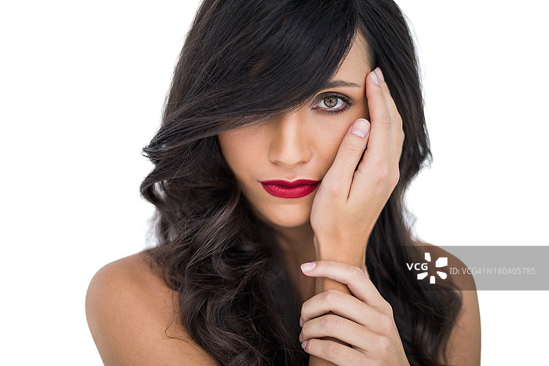 涂着红唇的魅力棕发女子抚摸着脸颊摆姿势图片素材
