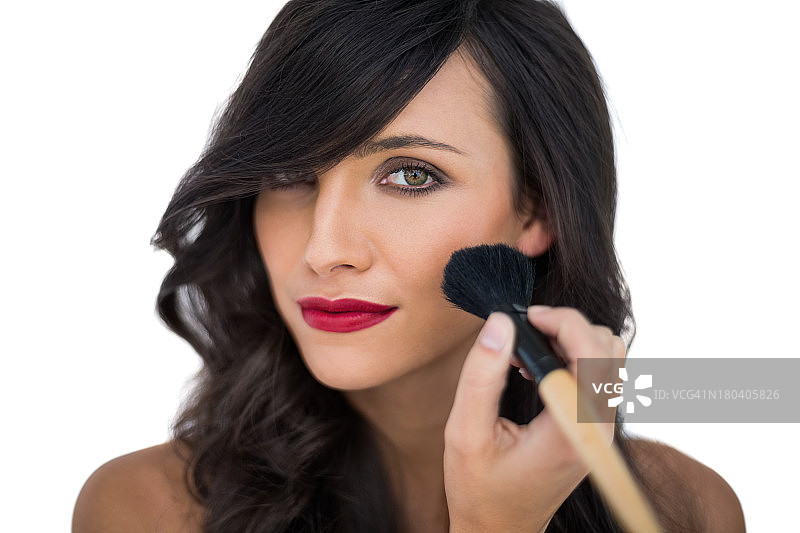 迷人的黑发女人在脸颊上涂腮红图片素材