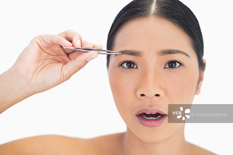 用镊子修眉毛而感到不适的模特图片素材
