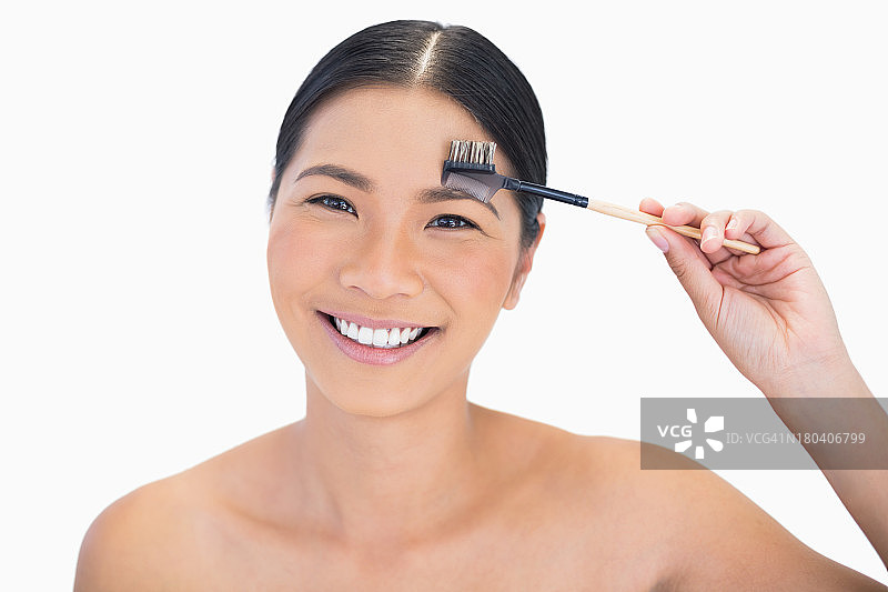 微笑的漂亮自然模特正在使用眉刷图片素材