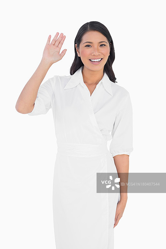 微笑的深色头发模特穿着优雅的连衣裙打招呼图片素材