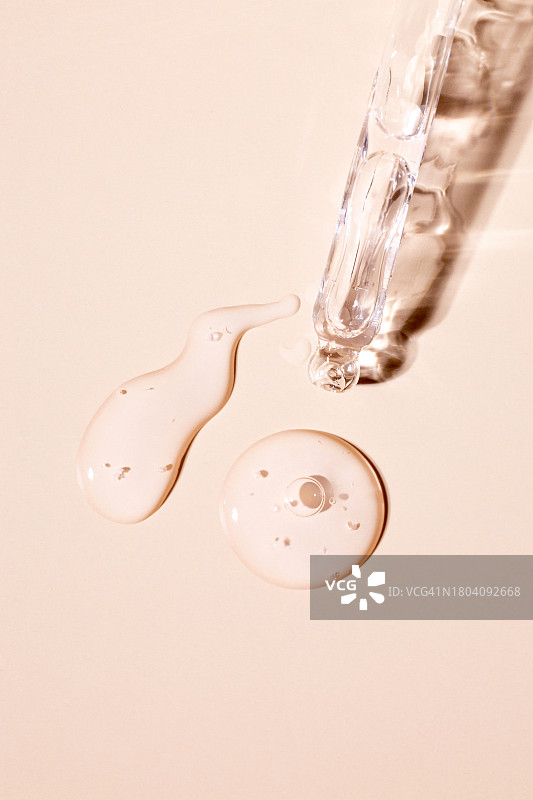米色背景上的透明精华液玻璃滴管图片素材