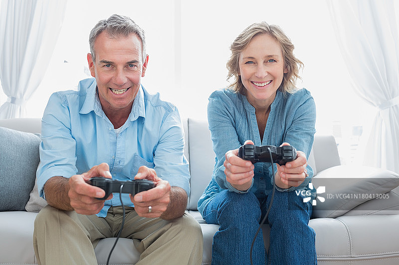 快乐的情侣在沙发上一起玩电子游戏图片素材