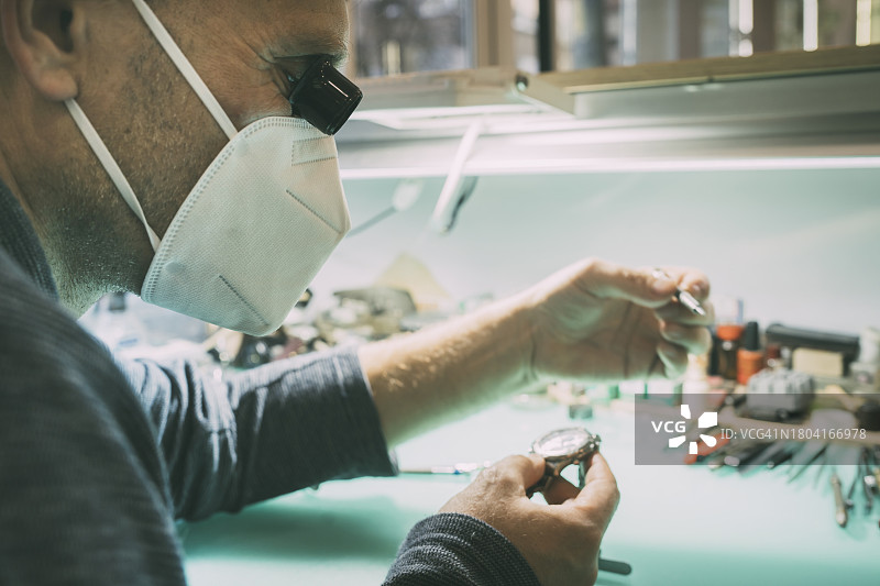 钟表匠在其工作室进行维修的特写图片素材