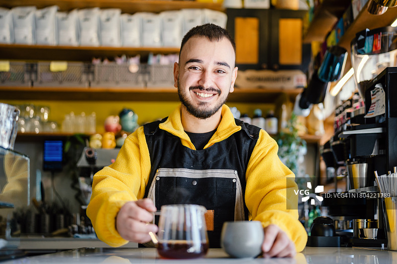 快乐微笑的咖啡师在咖啡店提供新鲜咖啡图片素材
