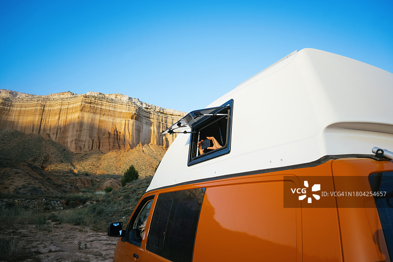 青少年男孩从露营车窗户探出身子，用智能手机拍照图片素材