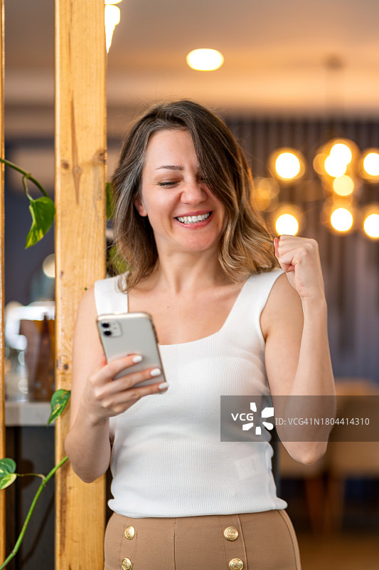 快乐的女人因手机中奖而欢欣雀跃图片素材