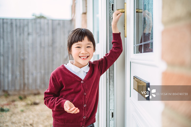 自豪的缺牙女学生对着镜头快乐地微笑。她拿着一颗掉落的乳牙回家向家人展示图片素材