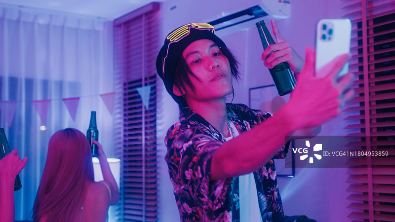 年轻亚洲男人在彩色家庭派对上自拍跳舞图片素材