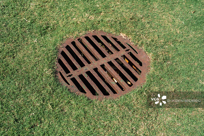 草地上的锈迹斑斑的沙井盖图片素材