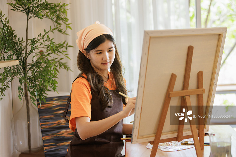 亚洲女艺术家专注于在绘画工作室的画布上用丙烯颜料绘画图片素材
