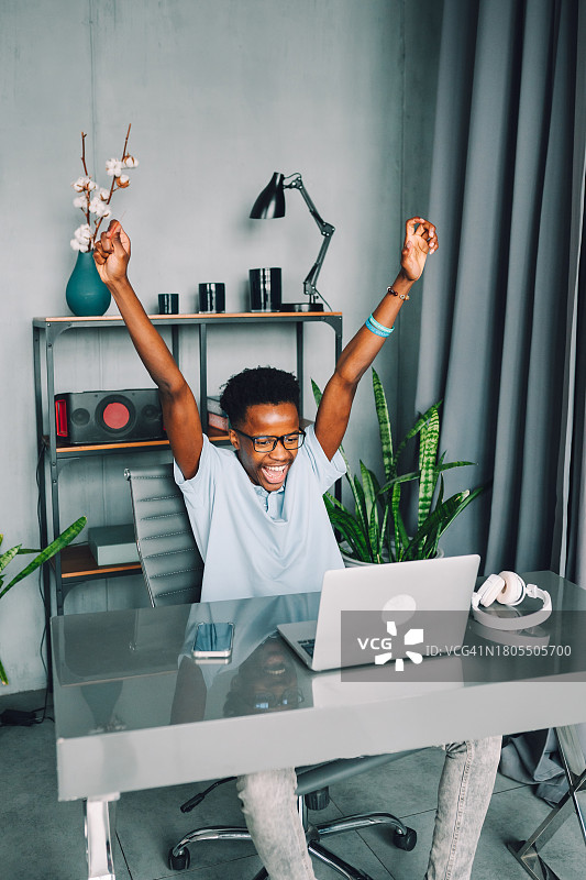 网上购物：年轻人坐在笔记本电脑前，拿着银行卡，为成功的网购感到高兴图片素材