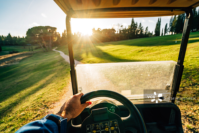 日落时分，一名男子驾驶高尔夫球车的视角图片素材