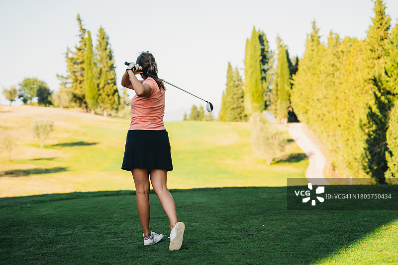 女高尔夫球手在高尔夫球场挥杆的背影图片素材