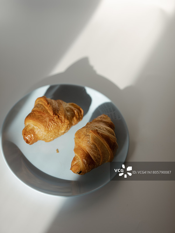 阳光下盘中的新鲜羊角面包图片素材