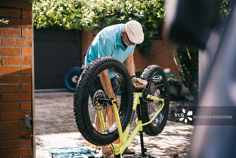 老年男人维护他的胖胎自行车图片素材
