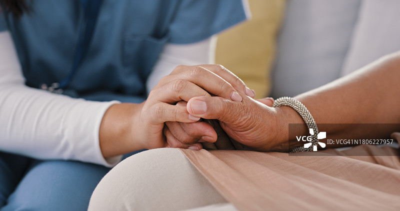 养老院中，护理人员握着老人的手，传递关爱与支持图片素材